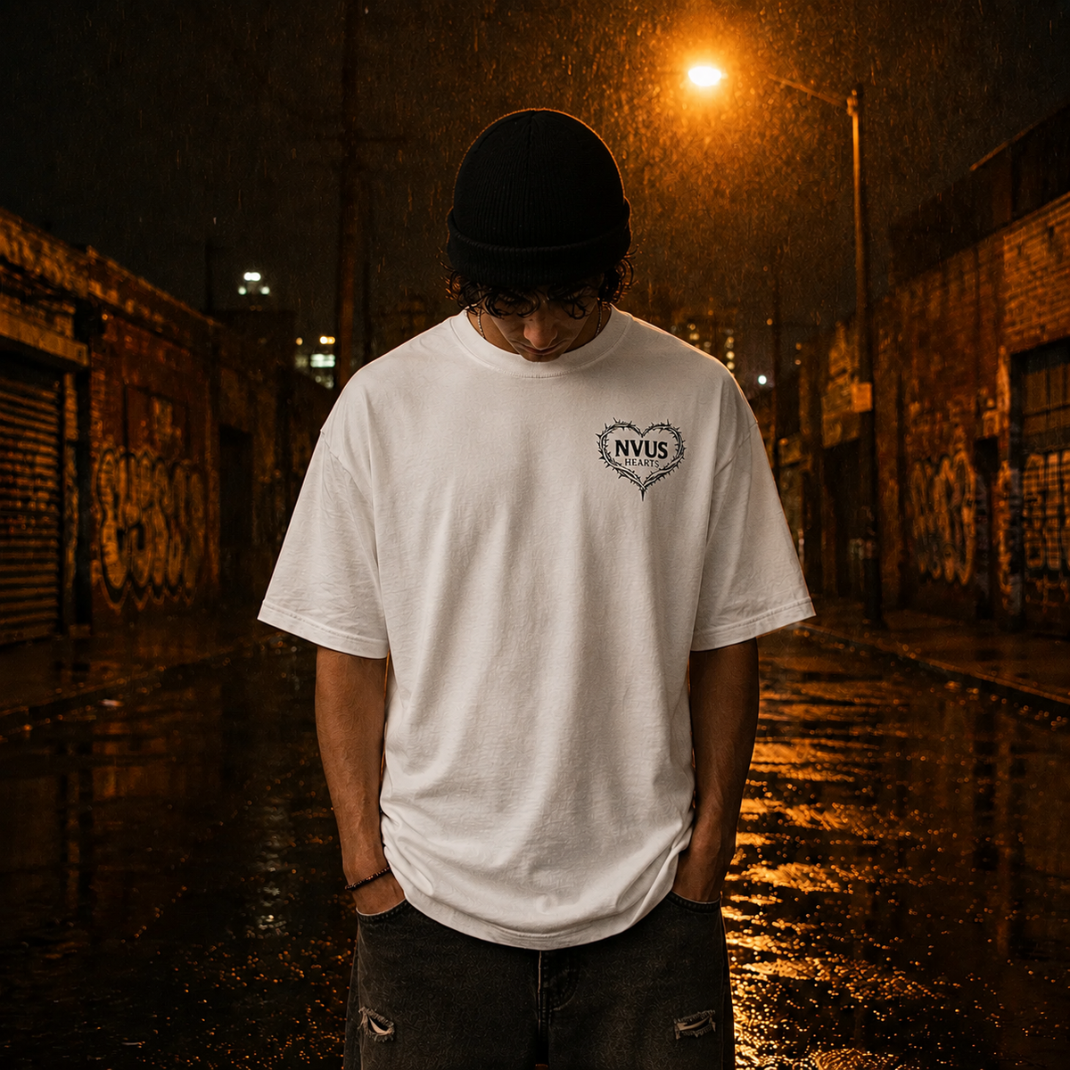 Person wearing a white t-shirt with a logo in a rain-soaked alleyway at night.